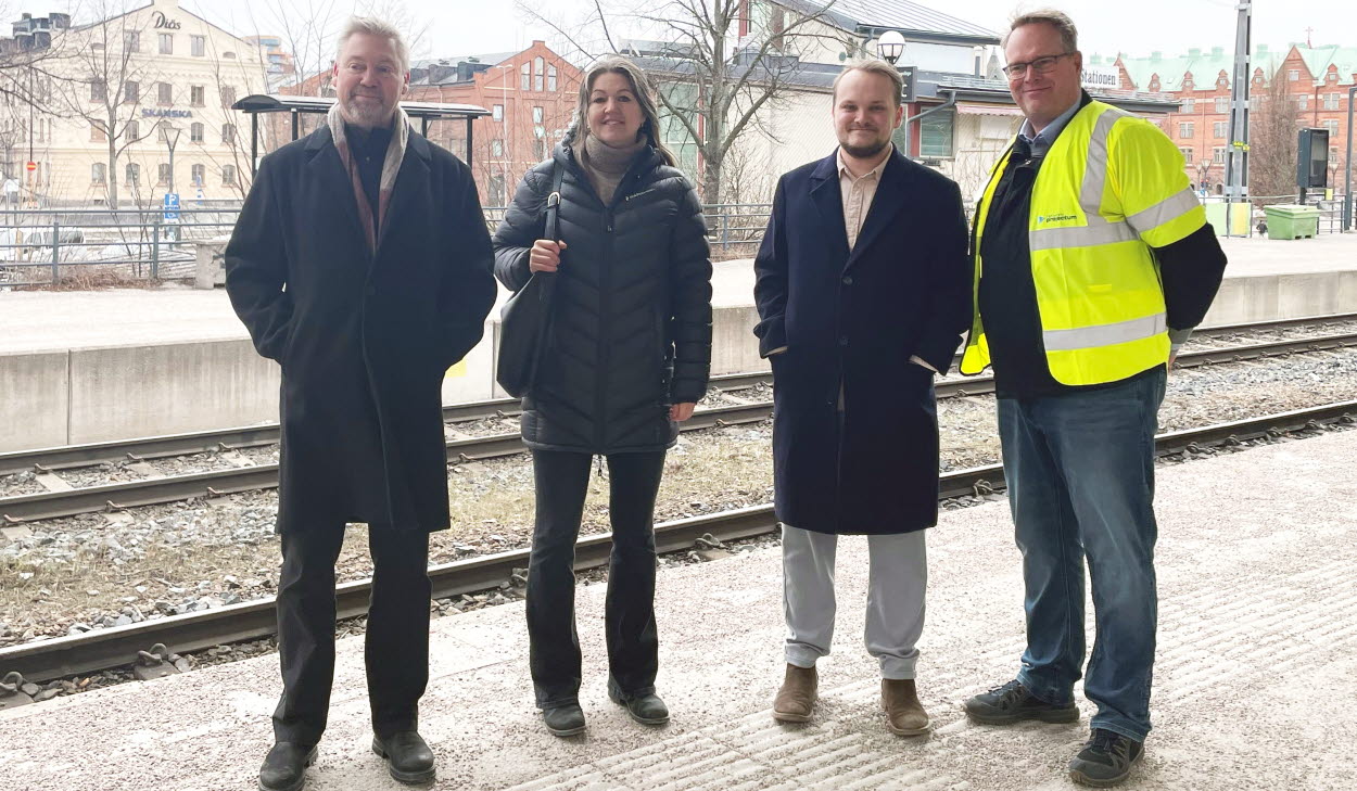 Fyra personer står på tågperrongen på Gävle central. Tre av dem bär mörka kläder och en person står med varselväst.