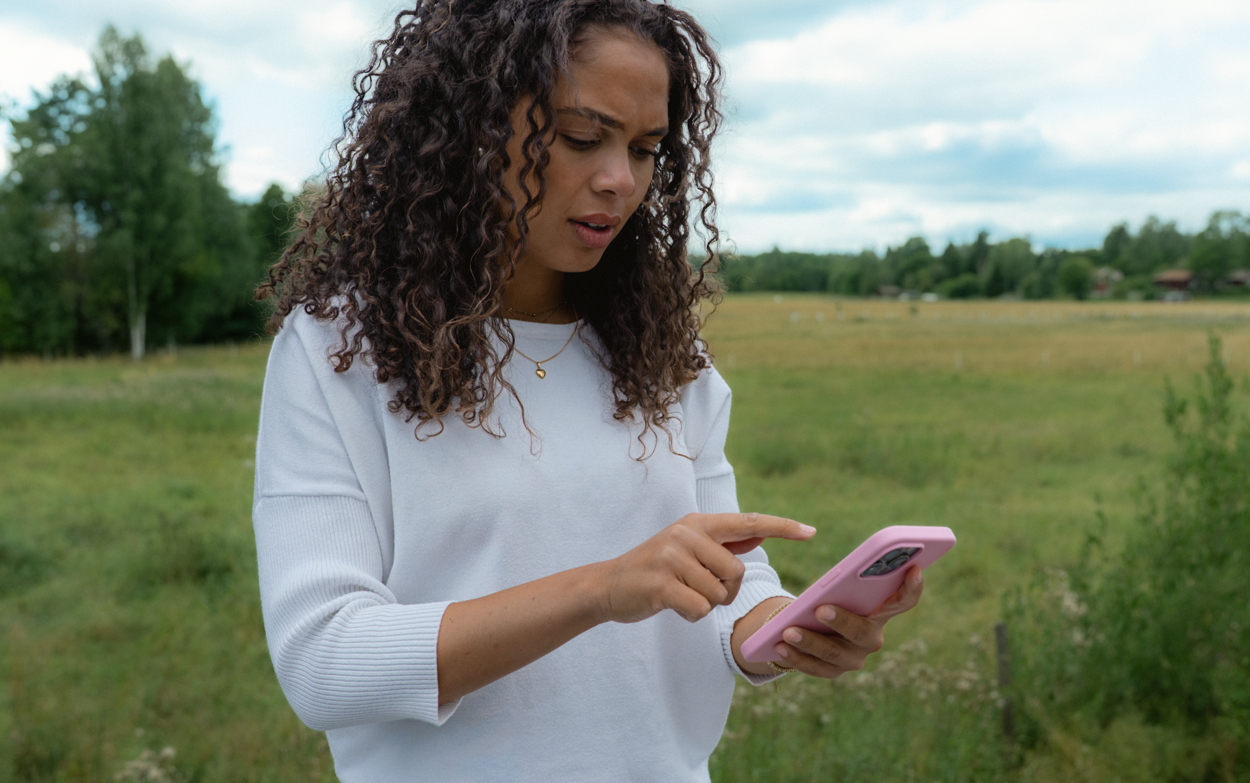 Kvinna står utomhus och använder en mobiltelefon.