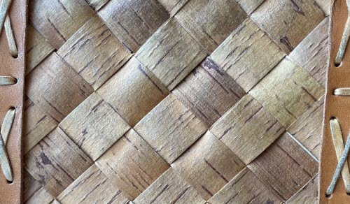 Närbild av flätat trämaterial med läderremmar.